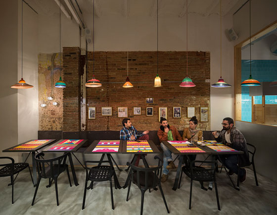 TANDOOR-restaurant-barcelona-by-isabel-lopez-vilalta Diners seated under colorful pendant lights at Tandoor Restaurant Barcelona, with exposed brick wall and industrial design
