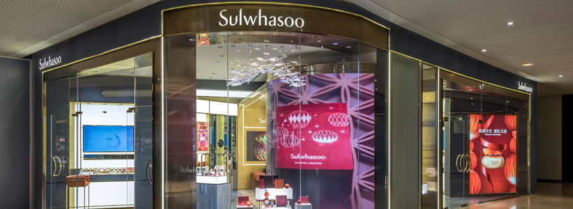 Beauty store Sulwhasoo a Guangzhou con espositori illuminati, lampadario floreale e finiture dorate