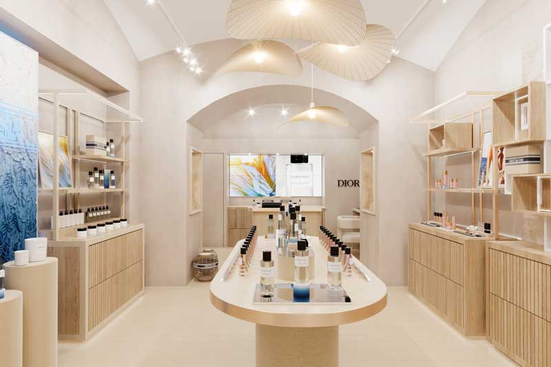 Interno della Beauty Boutique Dior a Capri, caratterizzato da arredi in legno chiaro, illuminazione soffusa e disposizione centrale di profumi su espositori curvi.