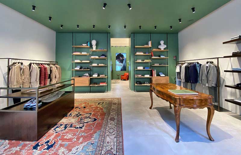 Interno elegante di uno store Pal Zileri, con arredi sofisticati, espositori ordinati e tappeto decorativo, simbolo del concept dei nuovi negozi in franchising