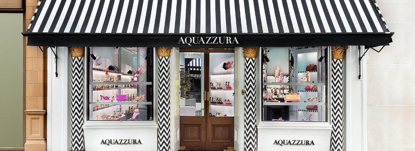 Facciata della boutique Aquazzura a Londra con tenda a righe bianche e nere e vetrine espositive