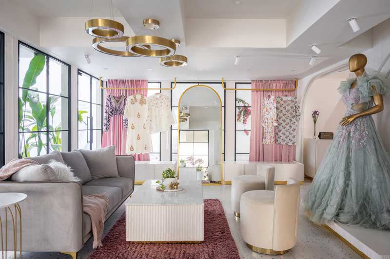 Area lounge della boutique Raslila con arredi dorati, pannelli scanalati e luce diffusa