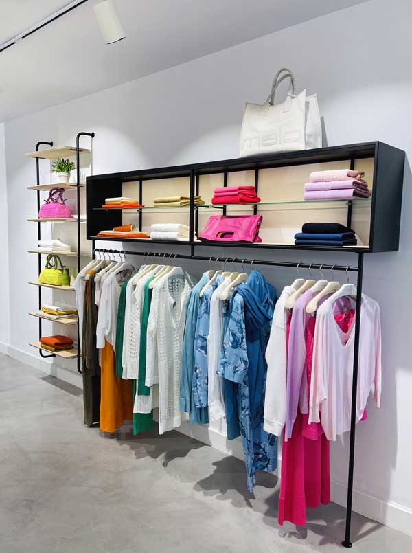 • vista interna della boutique Malo Cashmere a Marbella con abbigliamento e accessori in colori vivaci, suddivisi per tonalità, che riflettono l’eleganza e l’esclusività del brand.