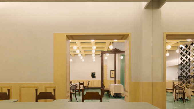 Interior dining room with pastel yellow walls, framed doorway and geometric ceiling lights inside Bitter Sweetie dessert shop in Tianjin