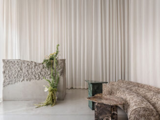 Raw concrete reception desk with textured surface, full-height white curtains and curved gobelin sofa at Stan yoga and barre studio in Kyiv