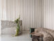 Raw concrete reception desk with textured surface, full-height white curtains and curved gobelin sofa at Stan yoga and barre studio in Kyiv