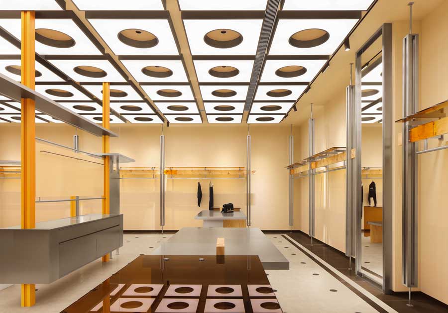 Soffitto con elementi circolari sospesi e illuminazione diffusa nel negozio Coscia