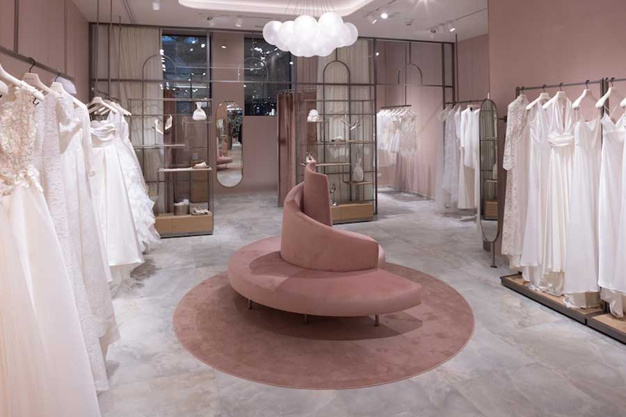 Sala espositiva del nuovo Atelier Emé a Milano con abiti da sposa bianchi, arredamento rosa elegante e illuminazione sofisticata