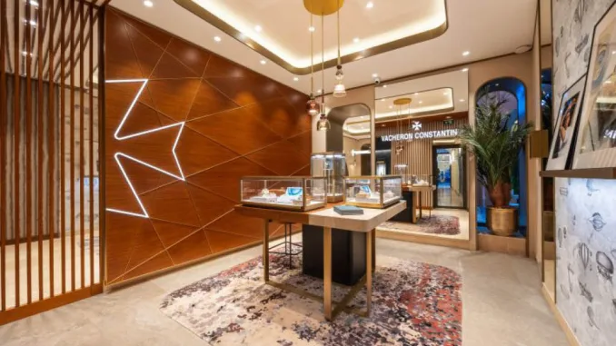 Interno della boutique Vacheron Constantin a Roma, con espositori illuminati, parete decorata con Croce di Malta retroilluminata e dettagli di design raffinato.