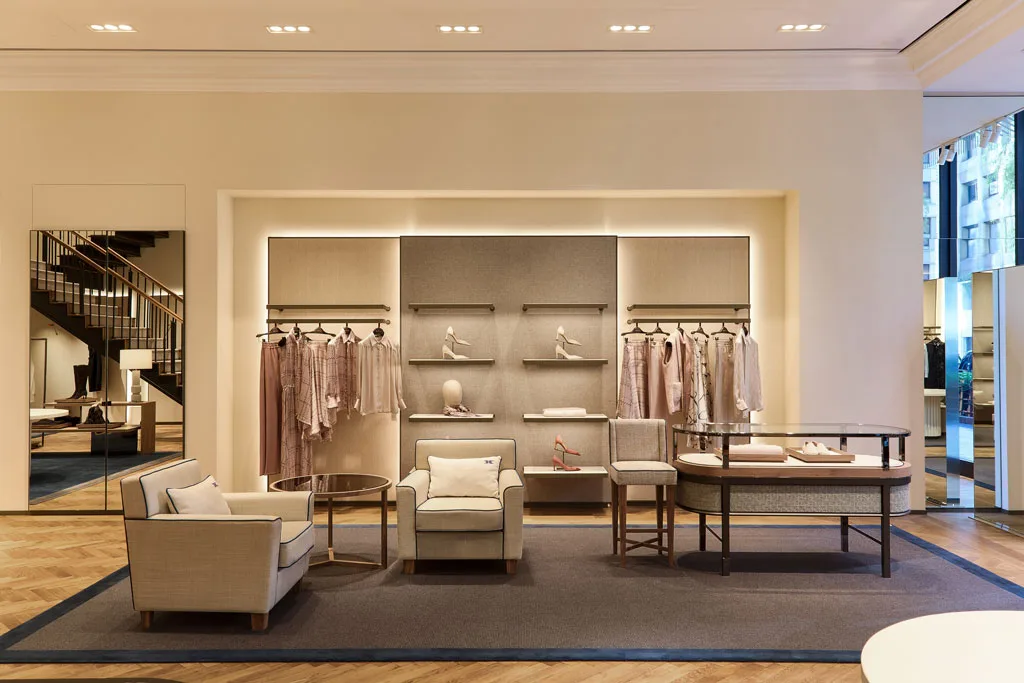 Area lounge del flagship store Kiton a Ginza, Tokyo, con arredi personalizzati, illuminazione soffusa e un design sofisticato. Gli espositori eleganti e i dettagli artigianali definiscono un ambiente di quiet luxury