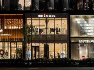 Facciata del flagship store Kiton a Ginza, Tokyo, con design trasparente e minimale, accanto ai brand di lusso Strasburgo ed Emporio Armani. L'eleganza architettonica risalta nel cuore del quartiere del lusso