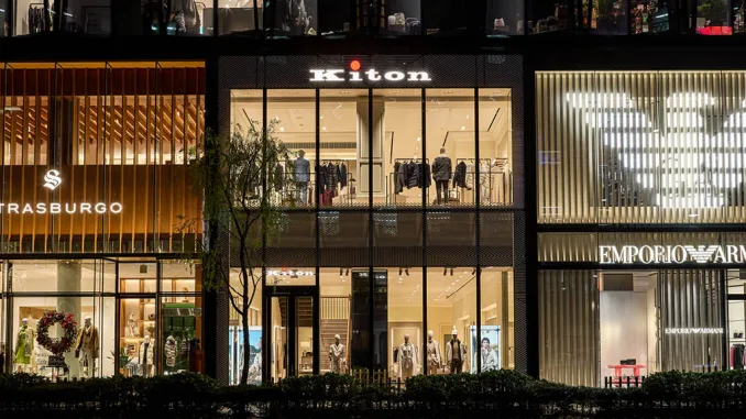 Facciata del flagship store Kiton a Ginza, Tokyo, con design trasparente e minimale, accanto ai brand di lusso Strasburgo ed Emporio Armani. L'eleganza architettonica risalta nel cuore del quartiere del lusso