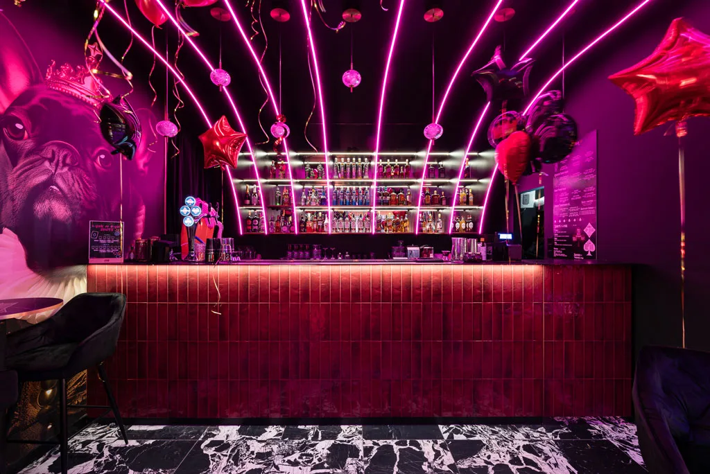 The bar counter serves as the focal point of the #King Cocktail Bar, with its glossy red-tiled finish reflecting light and creating an engaging visual experience. 
