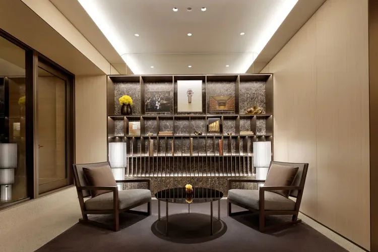 Salone VIP del flagship store Rolex Omotesando a Tokyo, con arredi eleganti, illuminazione raffinata e una libreria di design che enfatizza l'esclusività dello spazio.