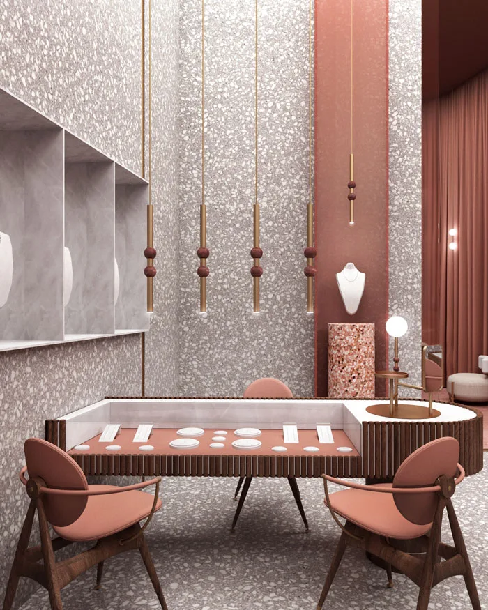 Bancone espositore per gioielli con vetrina integrata in un ambiente raffinato con finiture in terrazzo e dettagli in ottone, sedie in legno e pelle rosata, e un'illuminazione sospesa dal design contemporaneo.