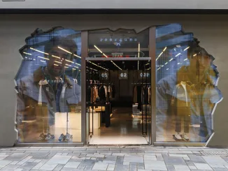 Facciata del concept store futuristico di Roarguns a Pechino con un design in cemento fratturato e schermi trasparenti che proiettano immagini digitali