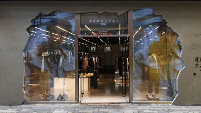 Facciata del concept store futuristico di Roarguns a Pechino con un design in cemento fratturato e schermi trasparenti che proiettano immagini digitali