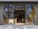 Facciata del concept store futuristico di Roarguns a Pechino con un design in cemento fratturato e schermi trasparenti che proiettano immagini digitali