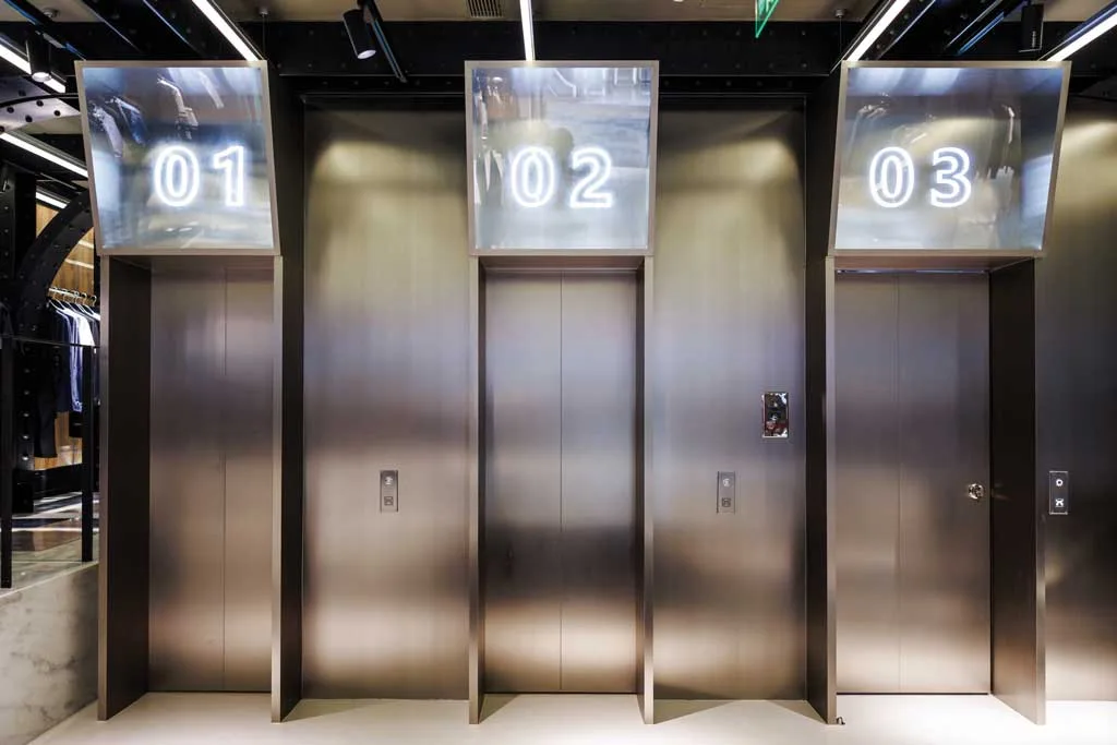 Entrance to the fitting rooms of Roarguns' futuristic concept store in Beijing, designed to resemble elevator lobbies with metallic doors and illuminated numbers.