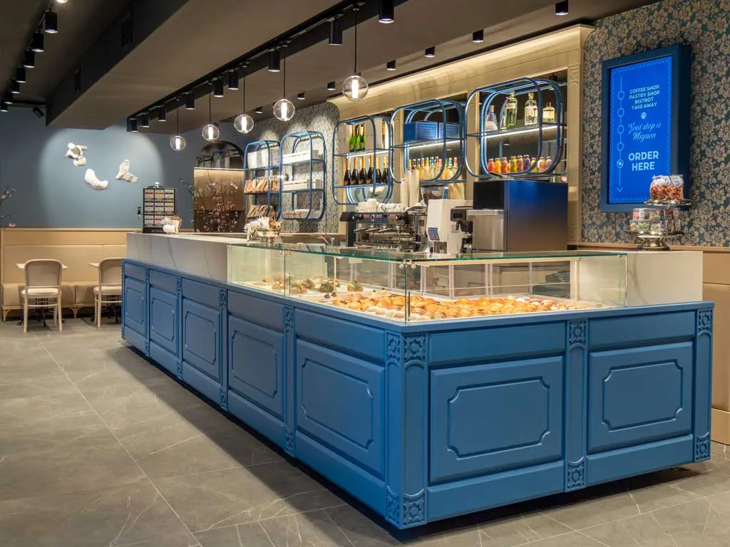 Interno della pasticceria napoletana Mignon a Milano, con eleganti scaffali dorati e banco espositivo in blu ispirato alle ceramiche di Vietri.