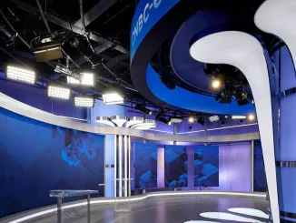 Scenografia moderna per studi TV: dettagli del design illuminotecnico e delle strutture metalliche dello studio CNBC-e.
