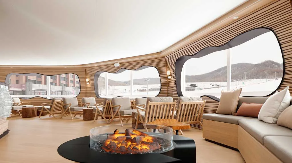 Lounge area with wooden seating and live-flame fireplace at the ReBIRD™ Service Center"