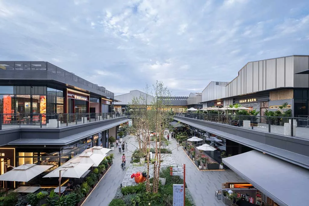 Vista della piazza esterna di SHAOXING PLACE by MixC, un ambiente moderno e accogliente con negozi, ristoranti e spazi verdi, progettato per favorire l’interazione sociale e il relax.