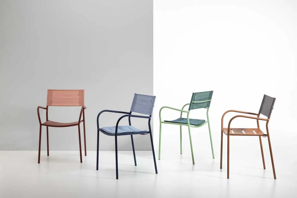 Sedie da esterno dal design moderno di Patrick Norguet per Vermobil, in diverse tonalità, disposte in un ambiente minimalista con sfondo bicolore bianco e grigio.