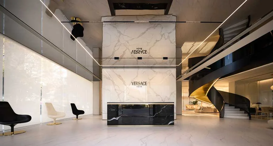 Interiors of the Versace Home flagship store in Qianjiang Century City, Hangzhou. Elegant design featuring marble floors and walls, sophisticated lighting, and a striking black and gold spiral staircase.
