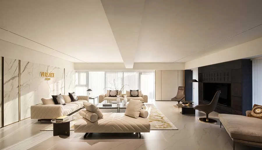 Luxury living room in the Versace Home flagship store in Qianjiang Century City, Hangzhou. Elegant design featuring quilted beige sofas, gold accents, and marble walls, illuminated by natural light through large windows
