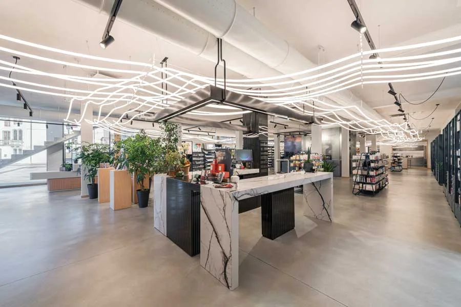 Interni della Farmacia Fecchio progettati da AMlab, con bancone in marmo, illuminazione LED ondulata a soffitto e layout moderno e spazioso, foto di Guglielmo Verrienti