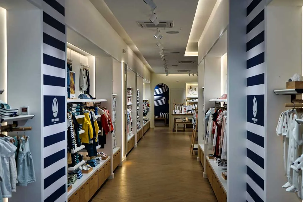 Corridoio centrale della boutique Petit Bateau a Roma con espositori ordinati e illuminazione soffusa