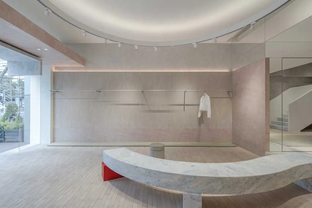 Interior view of the AVVENN concept store in Shanghai with a curved stone bench, backlit display wall and domed ceiling with track lighting