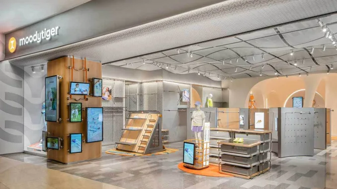 Ingresso del concept store moodytiger con soffitto ondulato, display multimediali e layout modulare, progettato da Sò Studio per il retail dedicato ai bambini