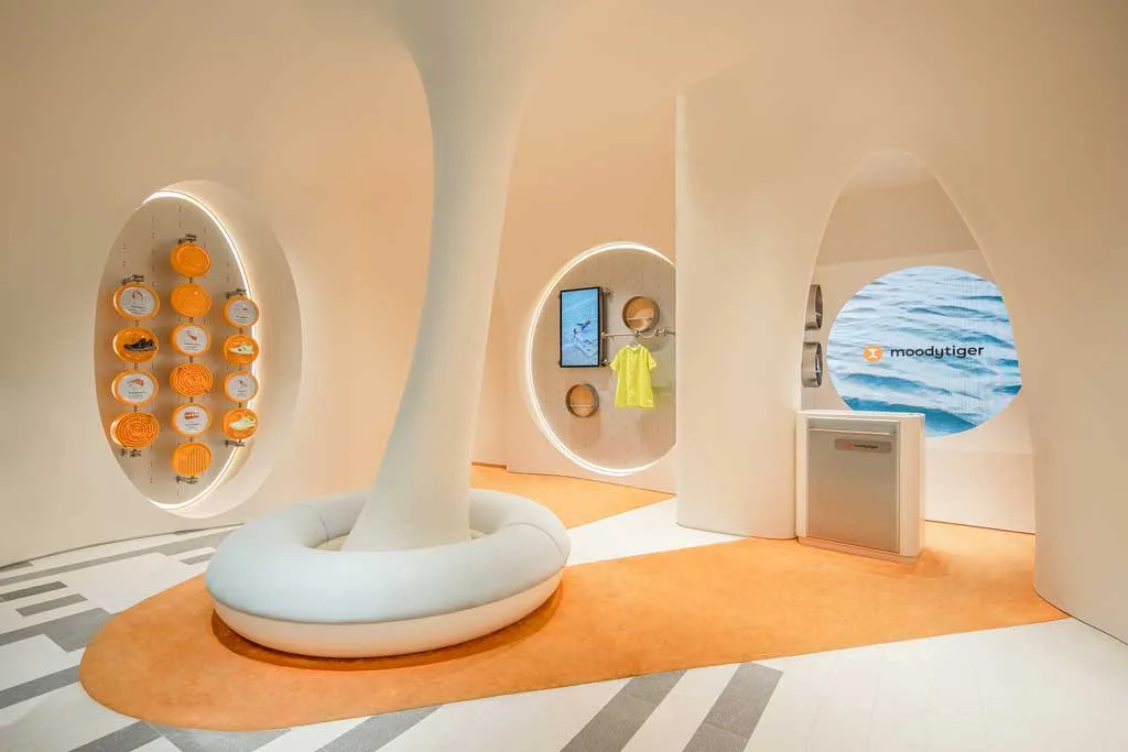 Zona lounge centrale del concept store moodytiger con seduta circolare e pareti organiche illuminate, esempio di design emozionale per bambini