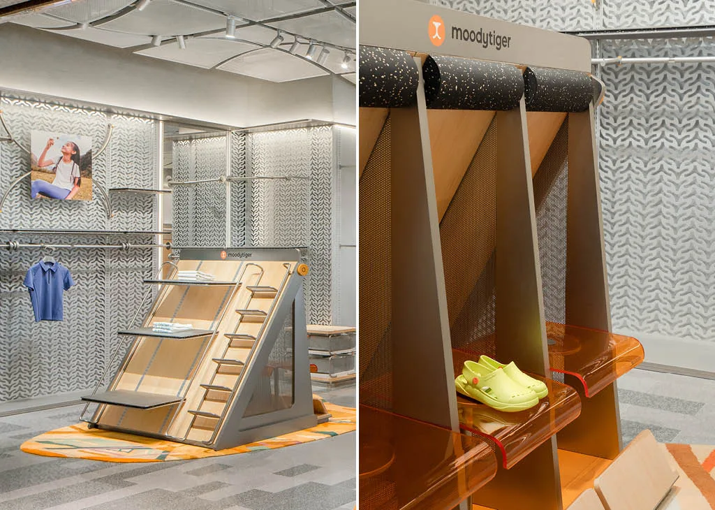 Dettaglio degli espositori inclinati e scaffali modulari nel negozio moodytiger, con texture tecniche e arredi pensati per il retail di abbigliamento sportivo per bambini