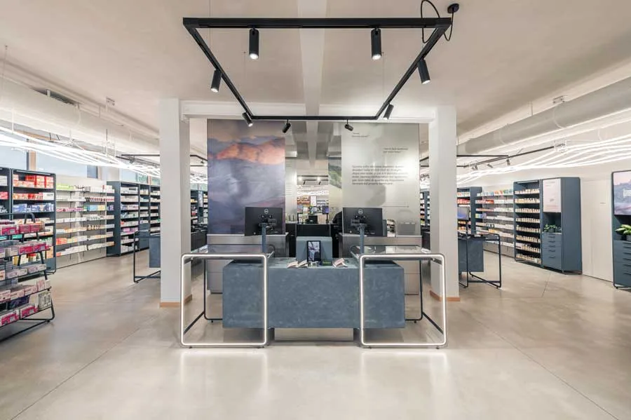 Postazioni cassa della Farmacia Fecchio progettata da AMlab, con arredamento moderno, grafiche artistiche e layout funzionale, esempio di progettazione farmacia innovativa.