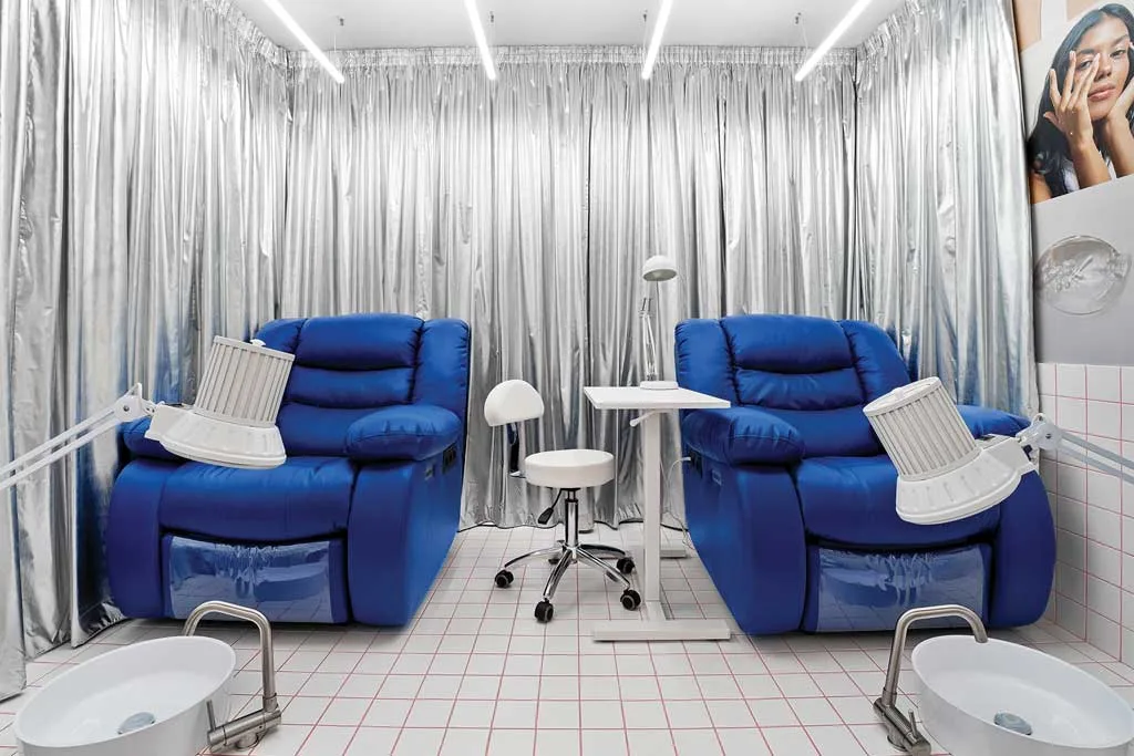 Pedicure area of the GxBar salon in Barcelona, featuring electric blue reclining chairs, metallic curtains, and well-lit stations, designed by Hvylya Design to offer comfort and relaxation.