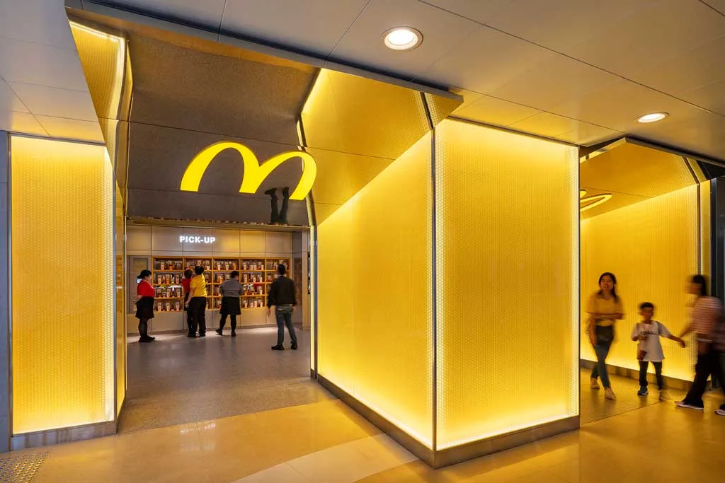 Ingresso McDonald’s Mood Engine a Hong Kong con pareti gialle retroilluminate e logo iconico