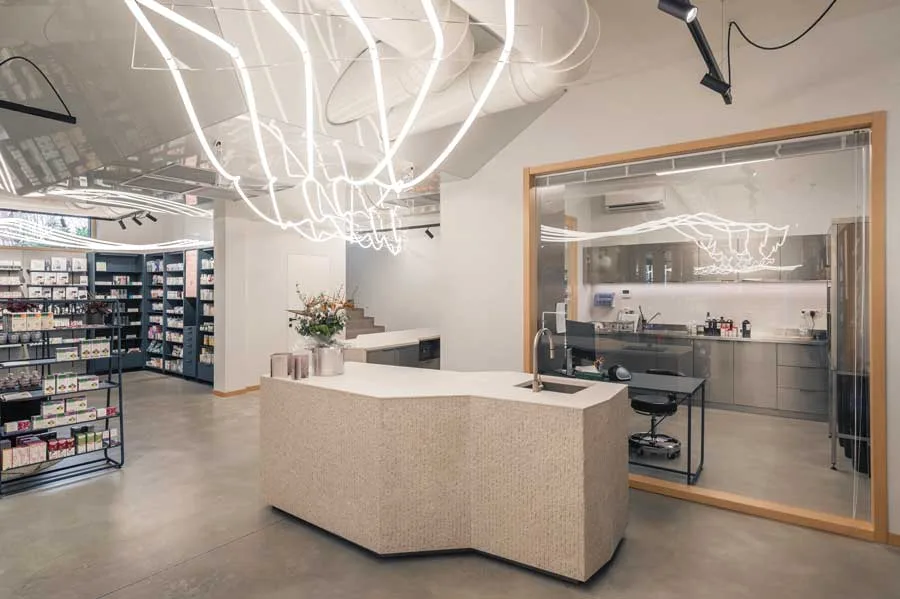 Area laboratorio della Farmacia Fecchio progettata da AMlab, con bancone su misura, vetrata interna e illuminazione LED decorativa, esempio di progettazione farmacia moderna.
