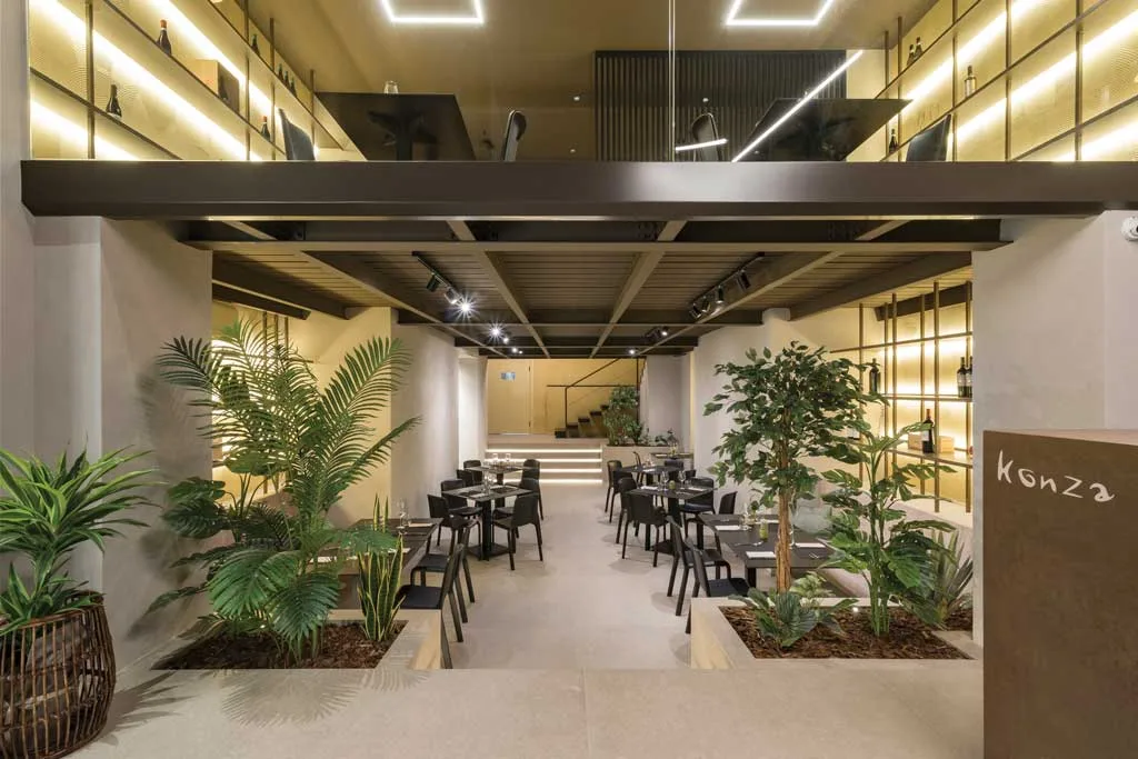 Vista centrale della sala con tavoli e piante integrate nell’arredo