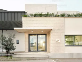 Ingresso del nuovo headquarter di Federico Giner progettato da Clap Studio, con facciata in mattoni chiari, struttura geometrica in metallo e vegetazione sulla terrazza