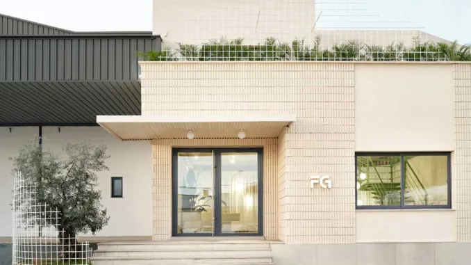 Ingresso del nuovo headquarter di Federico Giner progettato da Clap Studio, con facciata in mattoni chiari, struttura geometrica in metallo e vegetazione sulla terrazza