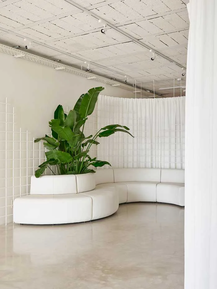 nuovo-headquarter-di-federico-giner-firmato-clap-studio_700x933 Area lounge del nuovo headquarter di Federico Giner con divano modulare bianco a forma curva, griglie metalliche decorative e pianta tropicale centrale, progetto Clap Studio