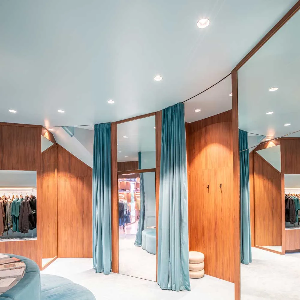 Fitting rooms of the Nude Project flagship store with baby blue velvet curtains, full-height mirrors and wood paneling