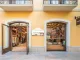 Facciata del flagship store Nude Project a La Roca Village con ingresso vetrato e libreria in legno visibile all'interno, parte del concept "Nude Library".