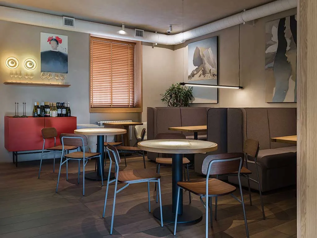 Interior of Ember Café in Saratov with upholstered seating, marble-effect tables, wooden chairs, contemporary artworks and suspended linear lighting