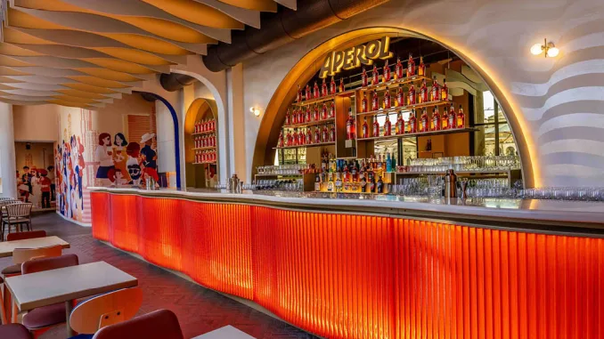 Il bancone iconico della Terrazza Aperol Milano con design arancione e bottiglie di Aperol in esposizione