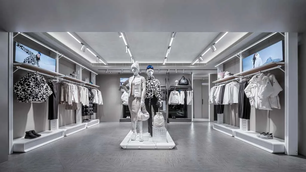 Area donna del flagship store DESCENTE a Harbour City con manichini centrali e capi invernali esposti in un ambiente dal design minimal e luminoso