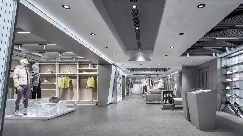 Area uomo del flagship store DESCENTE a Harbour City con arredi minimali, tonalità fredde e materiali high-tech ispirati a un’estetica futuristica